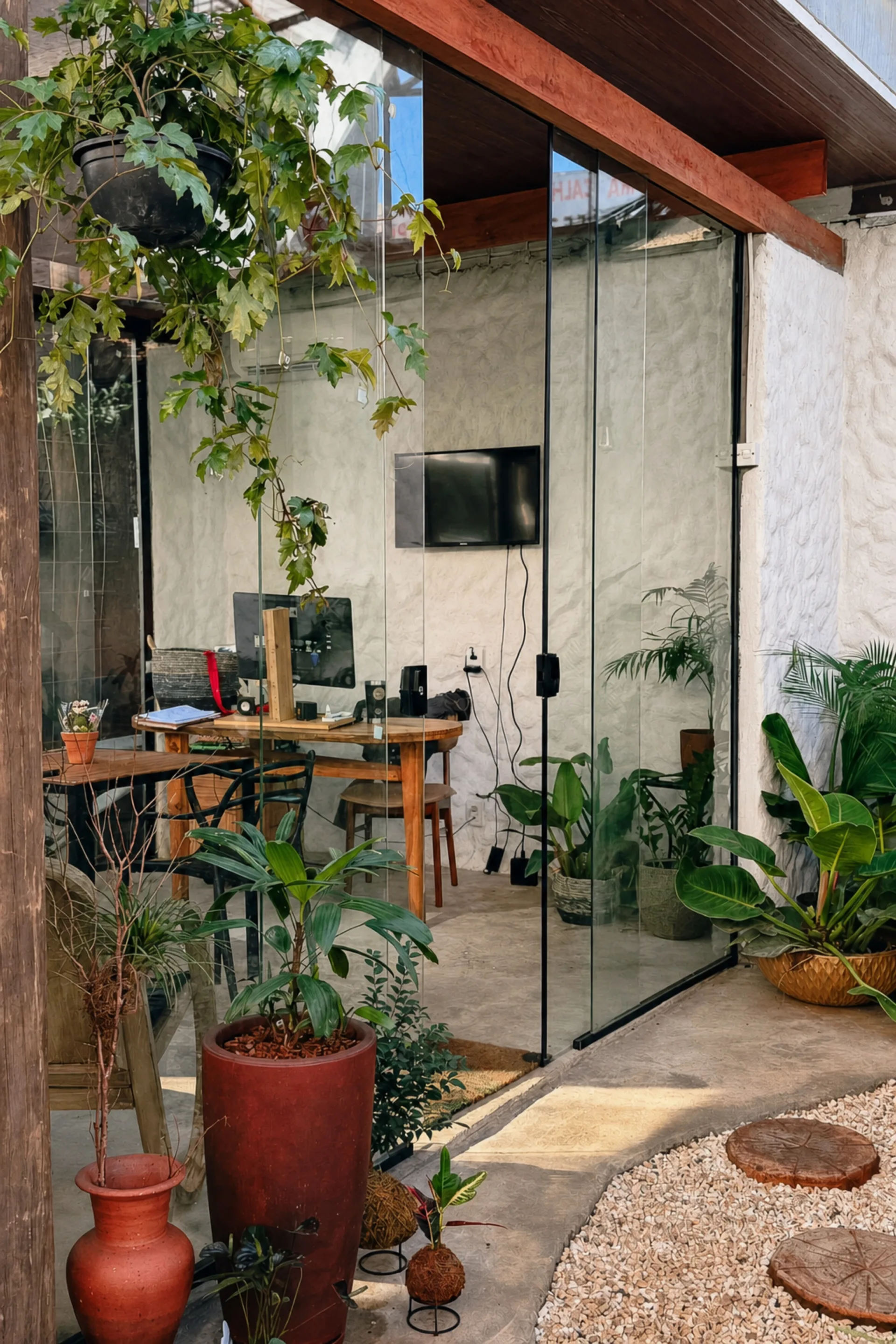 Coworking ArqVerdi com mesa de trabalho em diálogo com jardim, vidro e madeira.